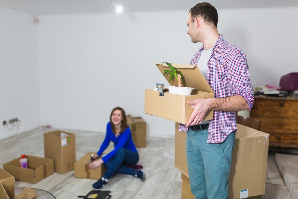 Couple unpacking boxes in a new home, organizing belongings after moving.