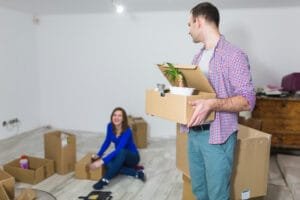 Couple unpacking boxes in a new home, organizing belongings after moving.